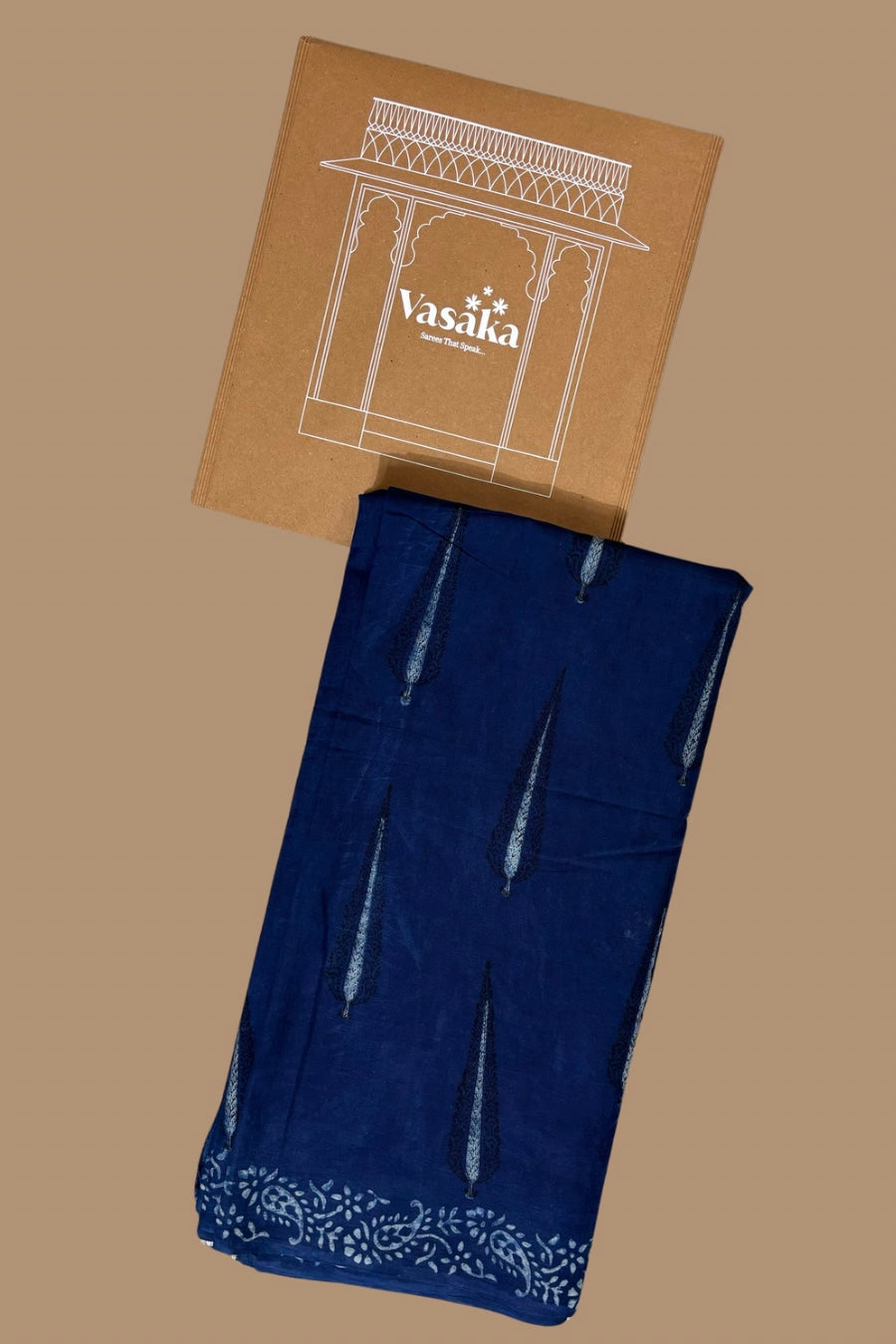 Indigo blue dabu hand block mulmul cotton saree with a detailed design at the border, laid flat on a beige background with the brand name 'Vasika' visible on the top.