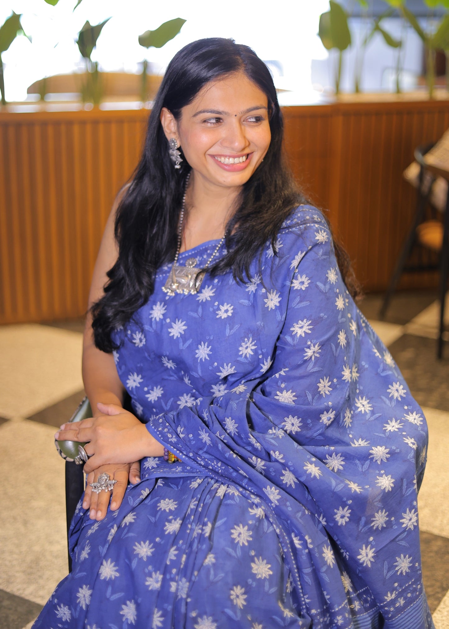 Woman wearing a blue saree with white patterns indoors.