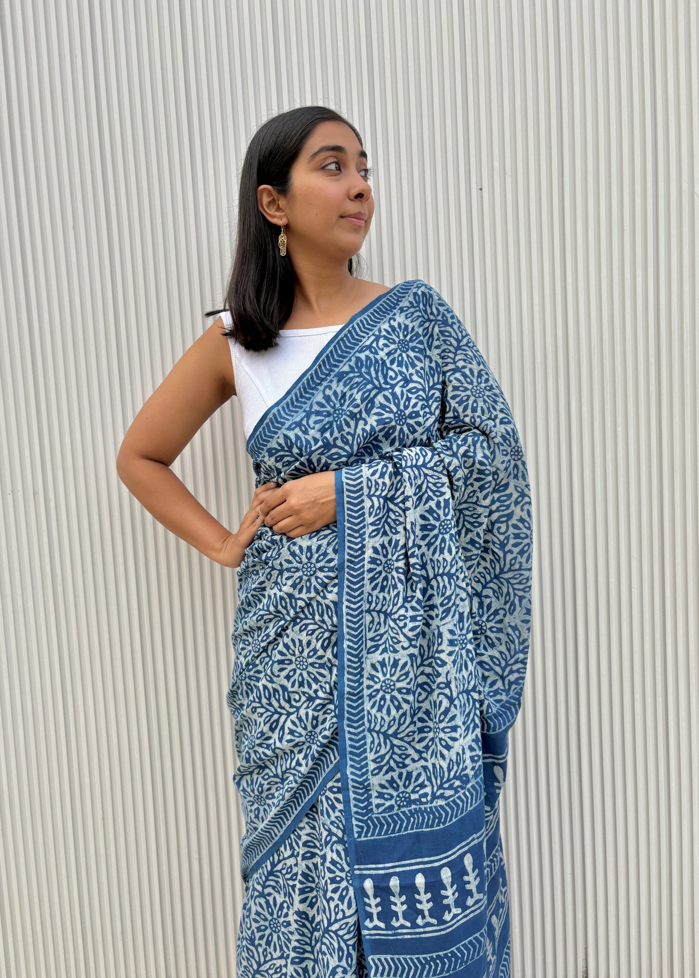 Woman wearing a blue and white patterned saree against a neutral background