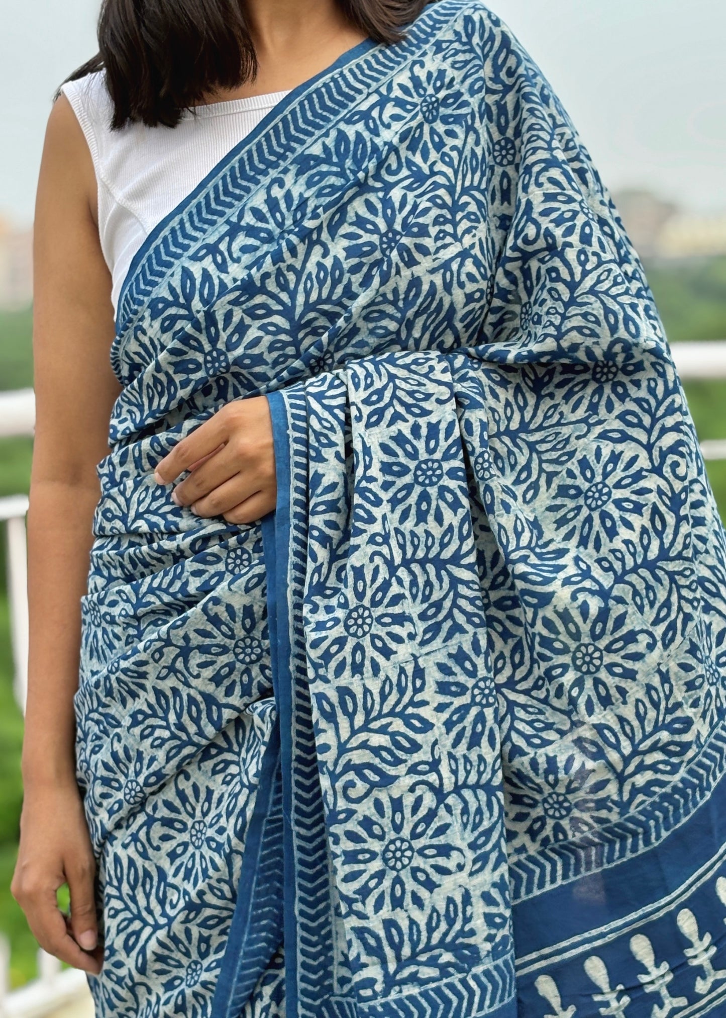 Person wearing a blue and white patterned saree with a blurred background