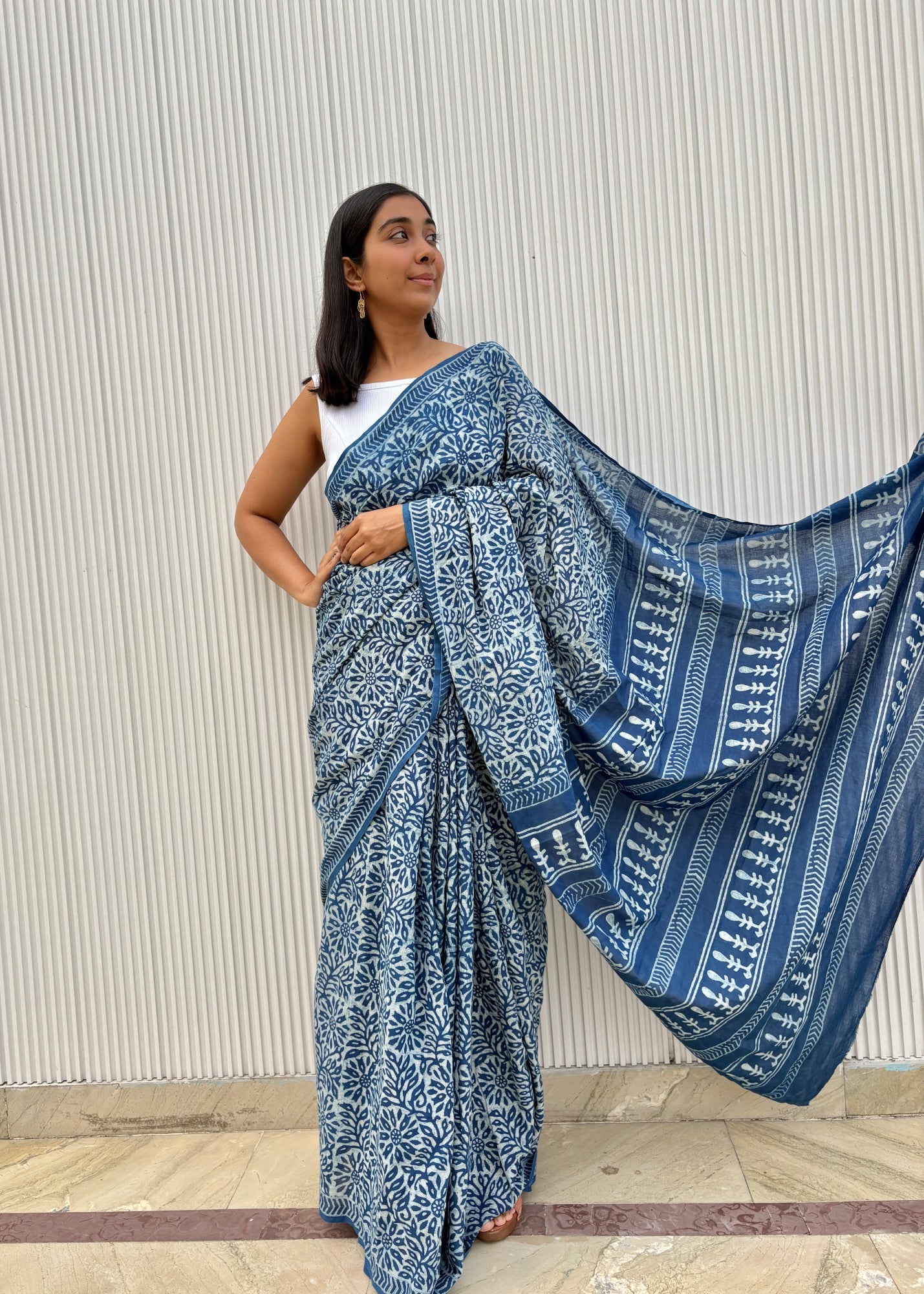 Woman wearing a blue patterned saree against a light background