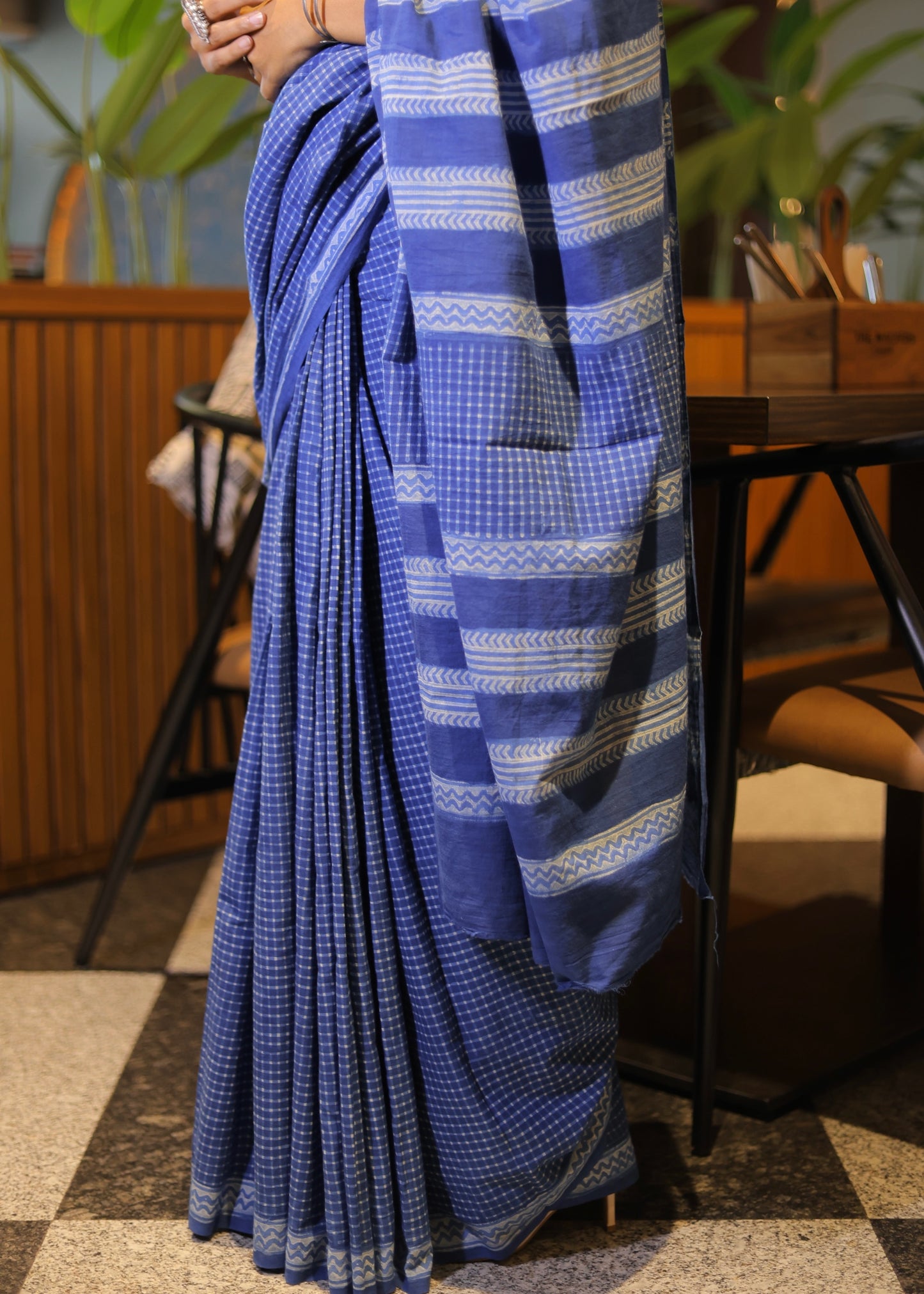 Blue saree with white patterns held by a person in an indoor setting